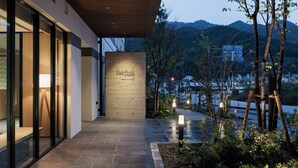 Una entrada de hotel moderna con fachada de madera, un letrero que dice "Fairfield by Marriott" y vistas de montañas al fondo.
