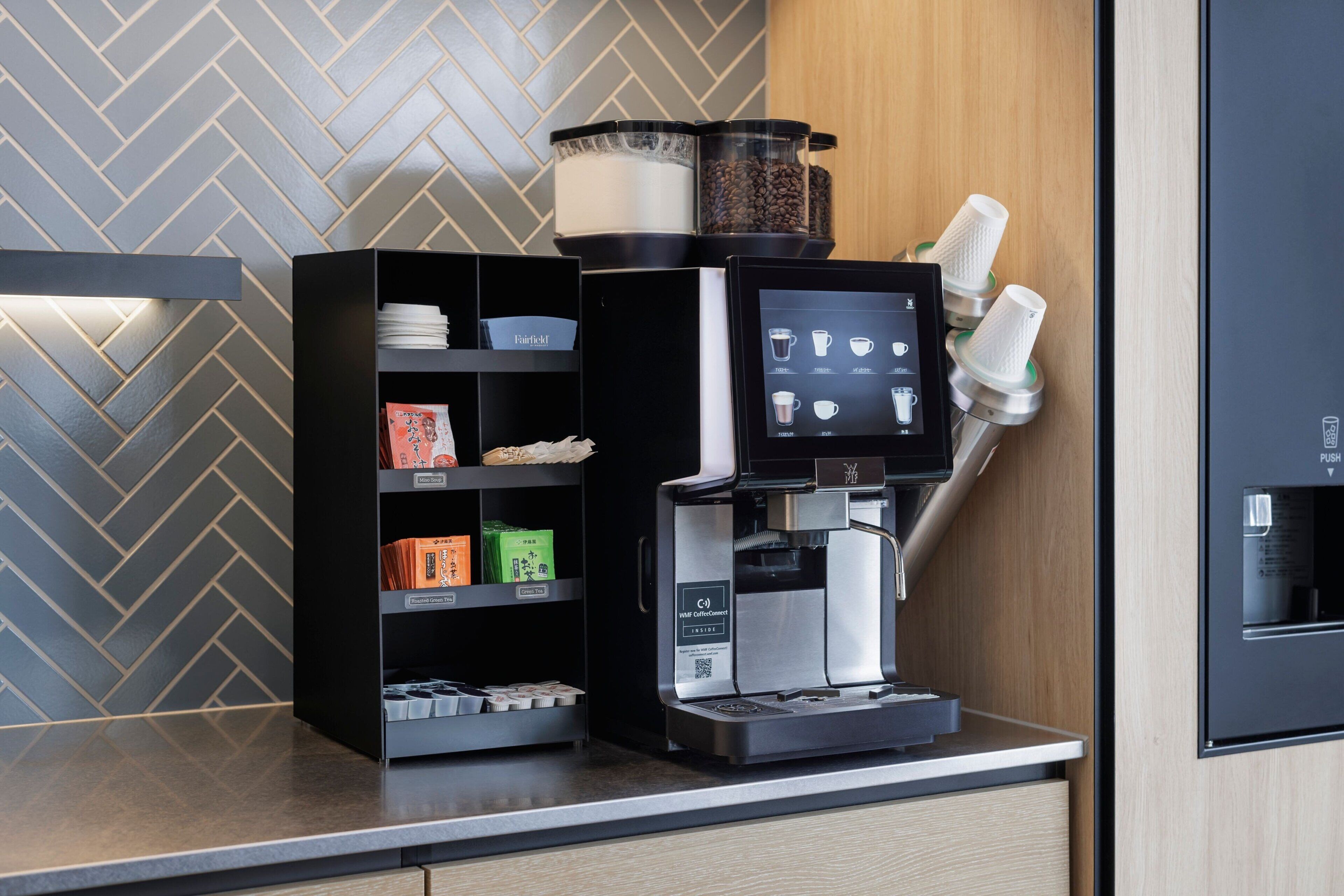 A coffee machine with a digital display, a coffee grinder, and a milk frother on a counter.