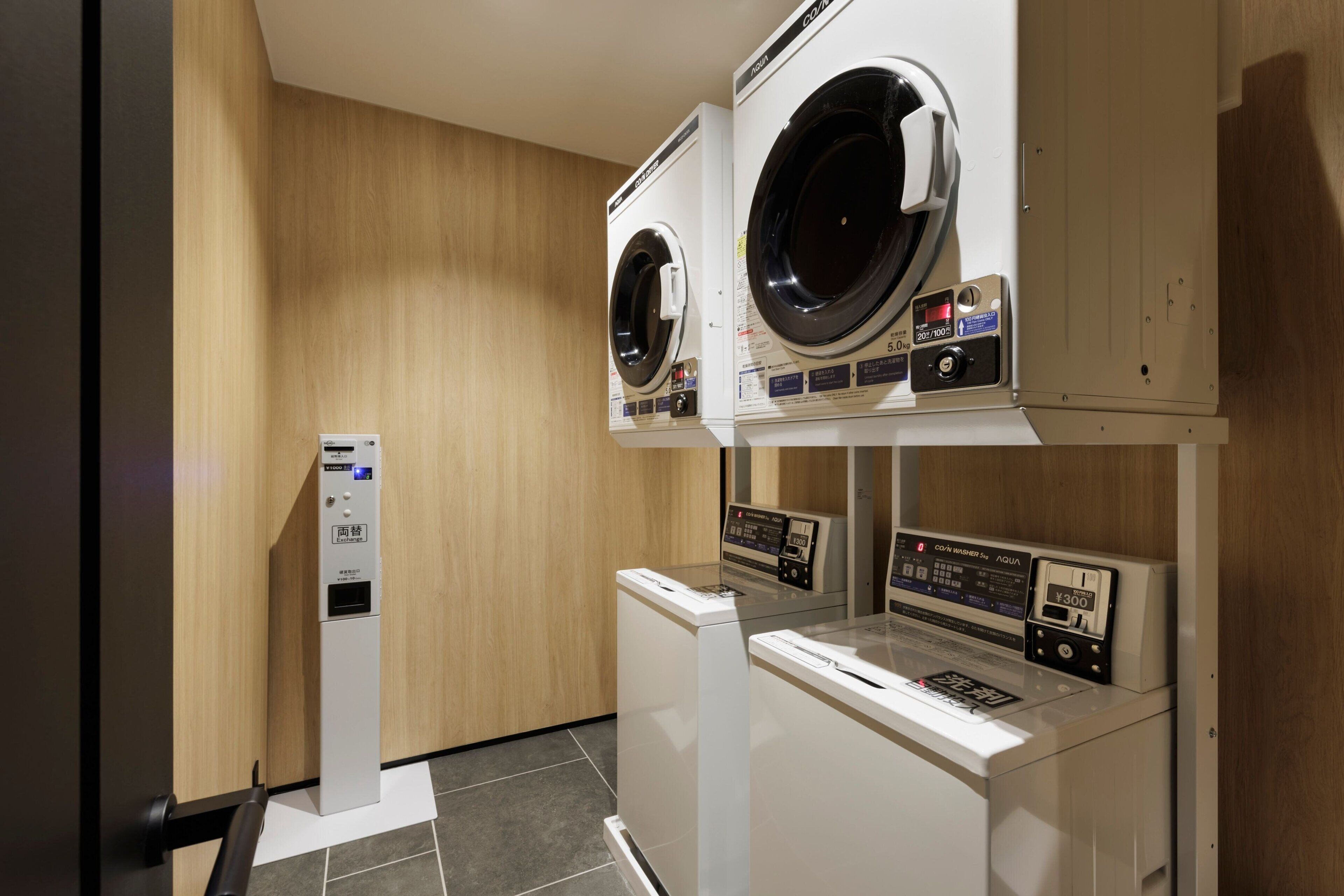A laundry facility with two front-loading washing machines and a dryer, equipped with digital control panels.