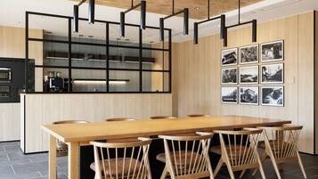 A modern kitchen with a wooden dining table and chairs, a built-in oven, and a black-framed hanging light fixture.