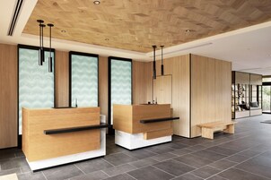 A modern reception area with wooden reception desks, black handles, and a bench.