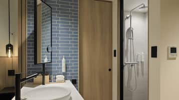 Ein modernes Badezimmer mit einem großen Waschbecken, einem Spiegel, einer Dusche und einer blauen Ziegelwand.