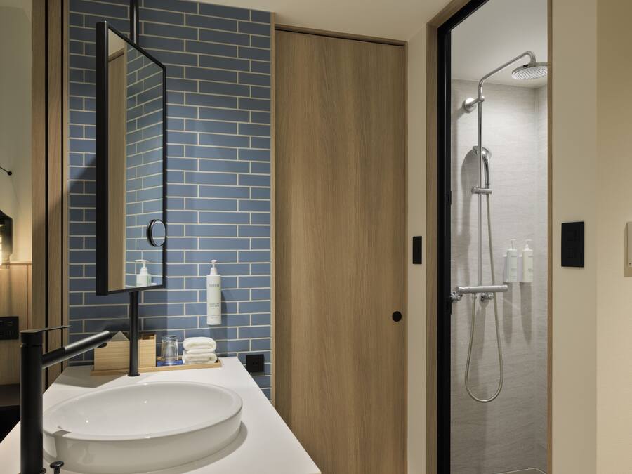 Ein modernes Badezimmer mit einem großen Waschbecken, einem Spiegel, einer Dusche und einer blauen Ziegelwand.