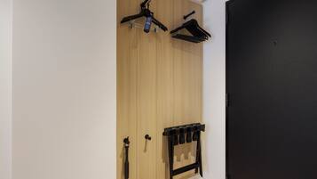 Une armoire avec un motif de panneaux en bois, une porte noire et un porte-manteau noir doté de crochets.