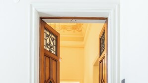 A hallway with a wooden door and a doormat with the text "CIURI DI STRATA DIMORA DI CHARME".