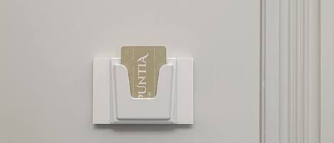 Un portal tarjetas blanco sujeto a la pared en un hotel, con una tarjeta que dice "PUNTA".