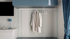 A modern bathroom with a glass shower enclosure, a white robe hanging on a rack, and a blue towel.