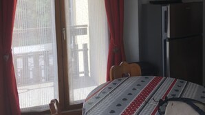 Een kamer met een bed, een televisie op een standaard, een koelkast en een schuifdeur met rode gordijnen.