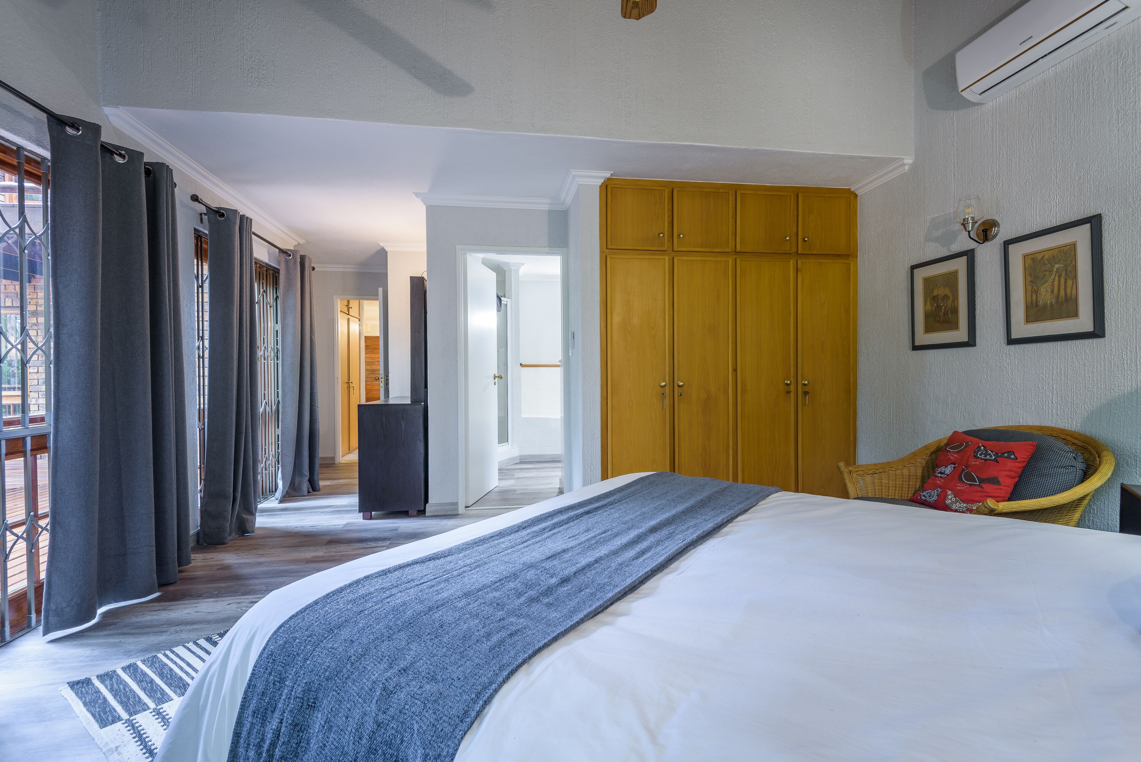 Une chambre avec un grand lit, une armoire en bois et un fauteuil en osier.
