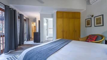Une chambre avec un grand lit, une armoire en bois et un fauteuil en osier.