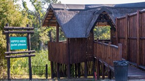 Een rustieke houten constructie met een bord waarop staat: “HIPPO HIDE, alstublieft stil”.