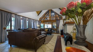 Een ruime woonkamer met een grote, bruine leren bank, een houten salontafel en een decoratieve vaas met bloemen.