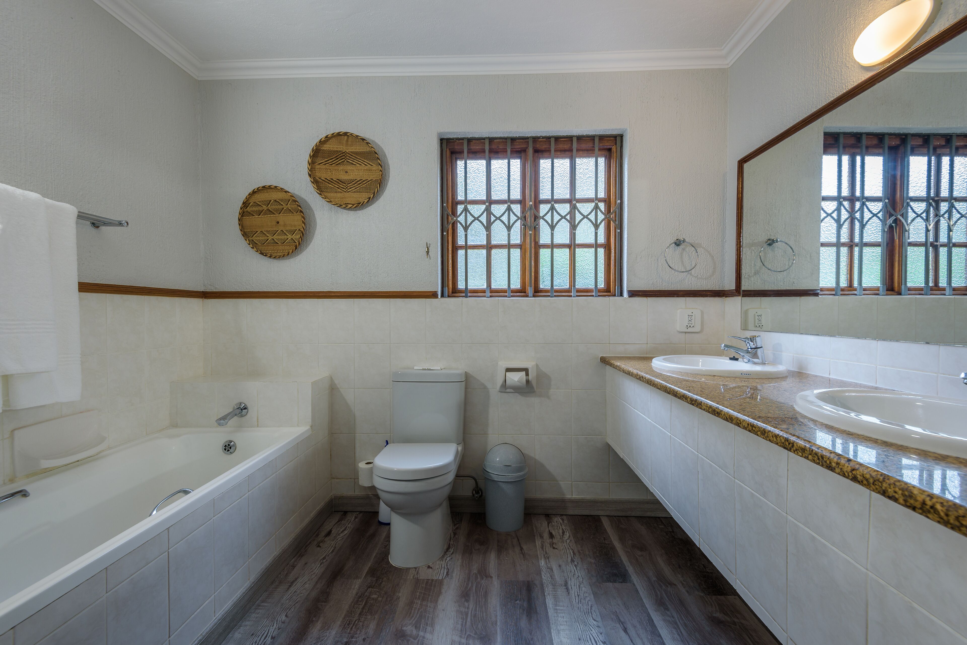 Un baño con bañera, inodoro y dos lavamanos.