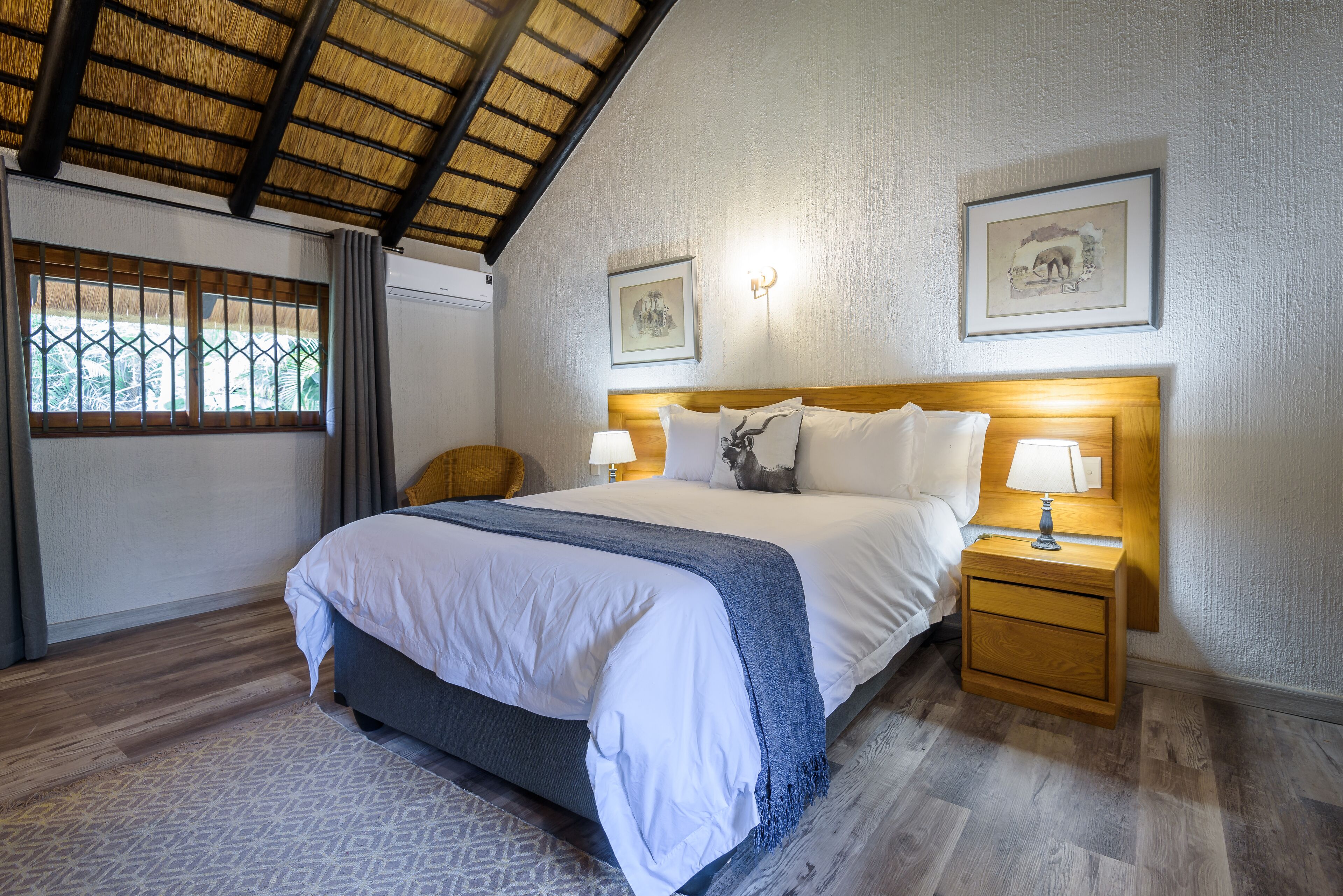A bedroom with a bed, bedside tables, a window with curtains, and framed pictures on the wall.
