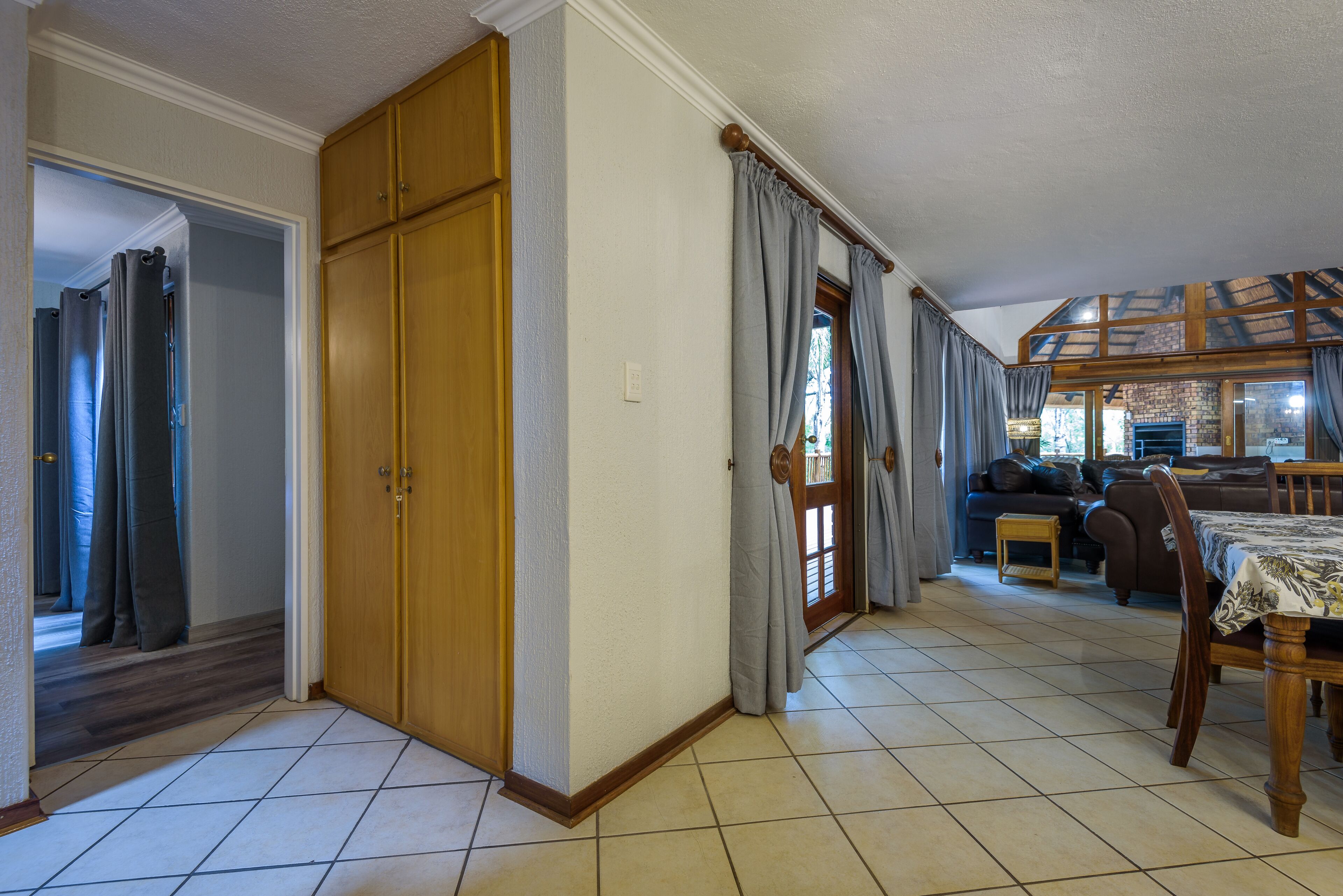 A spacious living area with a dining table, a sofa, and a wooden cabinet.