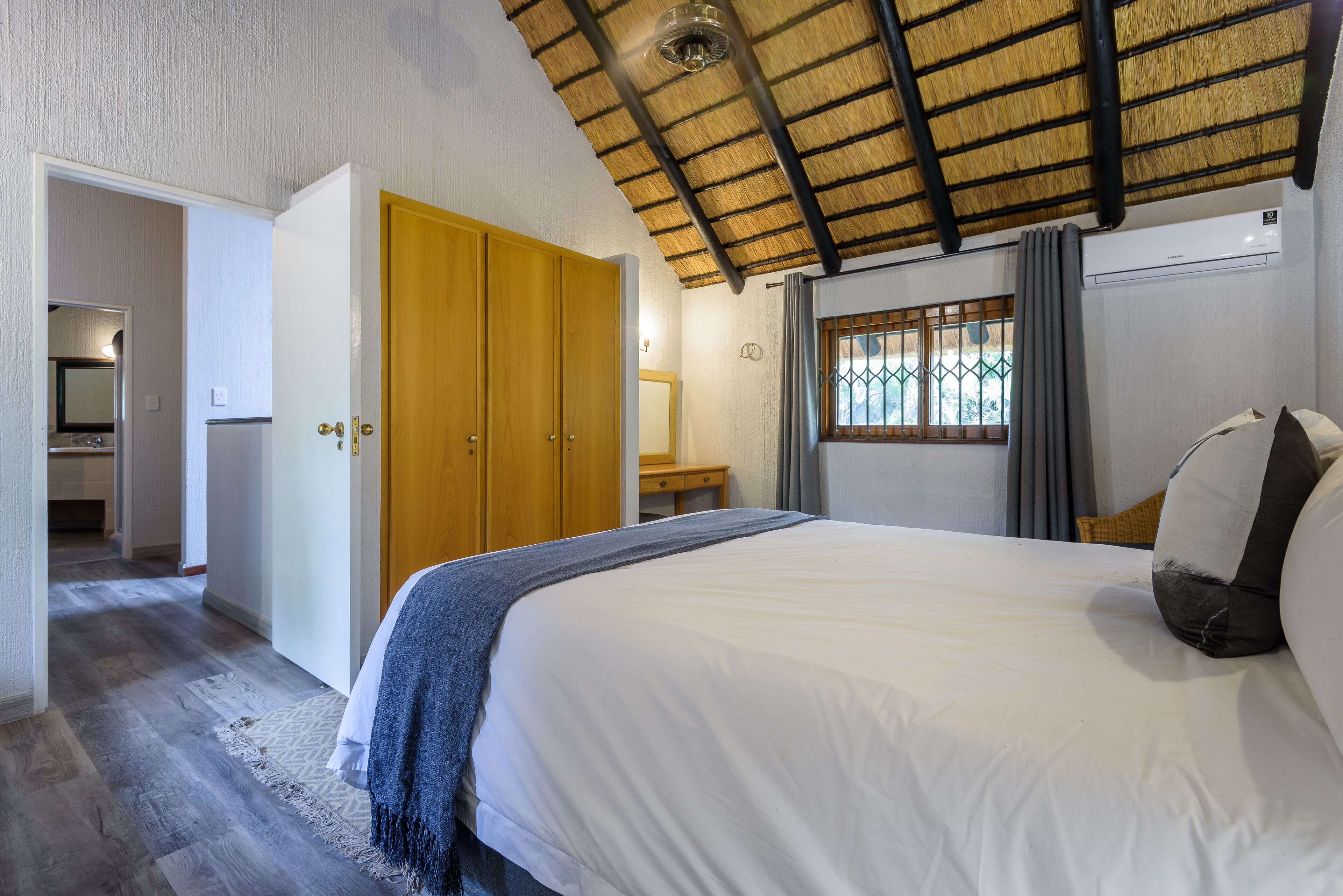 A bedroom with a bed, wooden wardrobe, and a window with curtains.