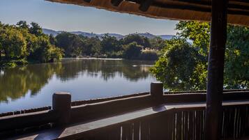 Une terrasse en bois surplombant un lac paisible, entouré de verdure et de collines.