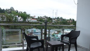 Un balcón con dos sillas y una mesa, con vista a una zona residencial con casas y vegetación.