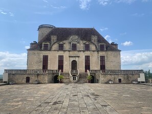 Een groot, historisch gebouw met een centrale ingang, stenen trappen en een binnenplaats.
