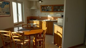 Una cucina con mobili in legno, un tavolo da pranzo con sedie e una finestra con un quadro.