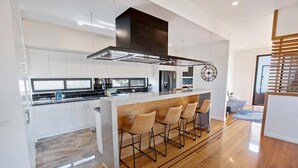 A modern kitchen with a central island, bar stools, and a clock on the wall.