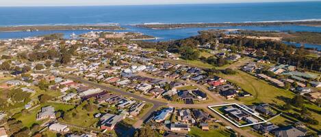 An aerial view of a residential area with houses, roads, and a large body of water in the background.