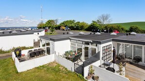 Een moderne woonwijk met meerdere huizen, een heldere lucht en een verre uitzicht op zee.