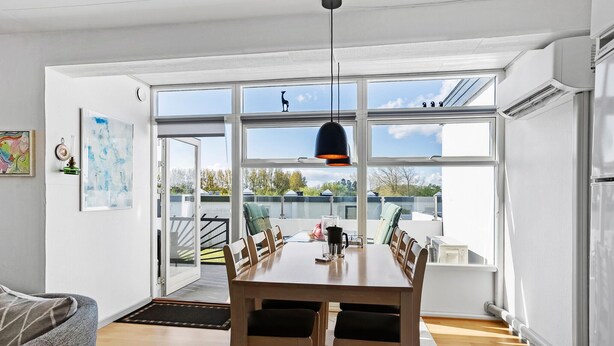 Een moderne keuken met een ruime eettafel, een hanglamp en uitzicht naar buiten.