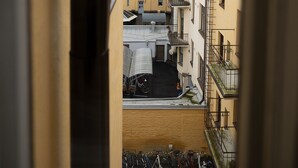 Una vista di una stretta via fiancheggiata da edifici, con una bicicletta parcheggiata in primo piano e una scala che conduce a un piano superiore.