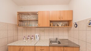 A kitchen with wooden cabinets, a stainless steel sink, and a countertop with various kitchen items. - Apartment Steindl (Vir)