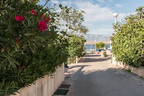 A pathway lined with greenery and a view of a body of water with mountains in the distance. - Apartment Steindl (Vir)
