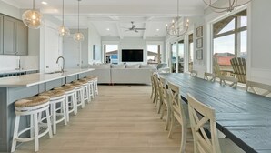 Una cocina moderna con una isla central, taburetes de bar y una mesa de comedor con sillas.