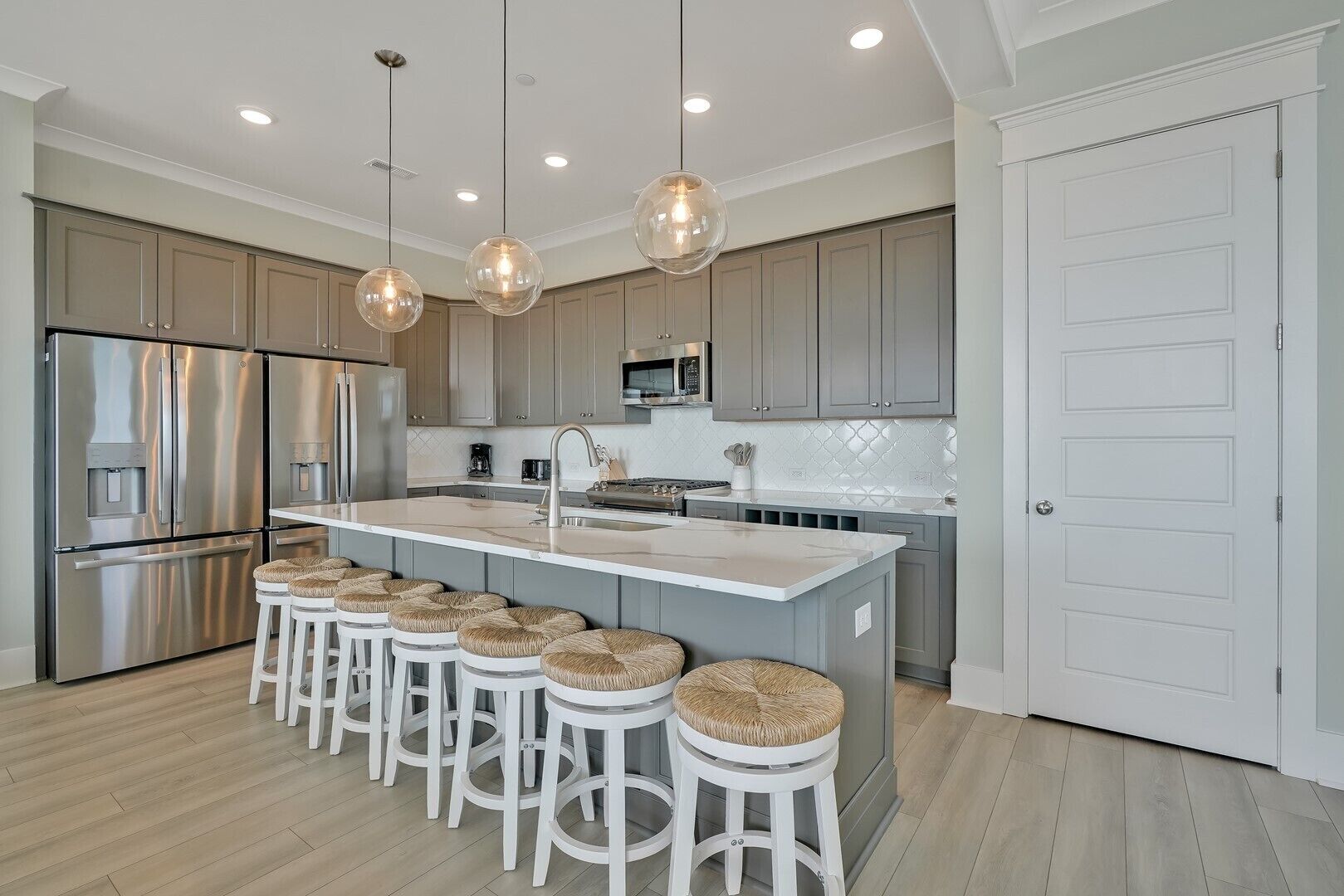 A modern kitchen with a central island, stainless steel appliances, and pendant lighting.