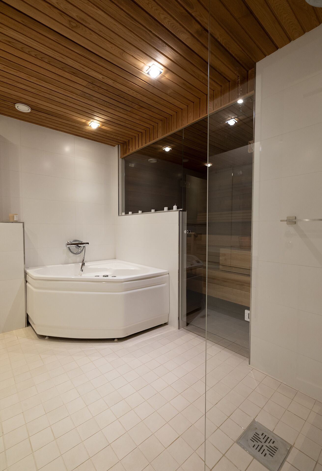 Et moderne badeværelse med et fristående badekar, en glasbrusekabine og loft i træ.