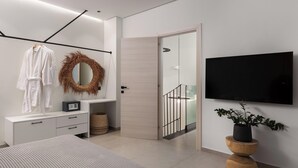 Une chambre moderne comprenant un lit, une télévision, un miroir, une armoire et une porte donnant sur un balcon.