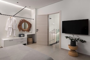 Ein modernes Schlafzimmer mit Bett, Fernseher, Spiegel, Kleiderschrank und einer Tür, die auf einen Balkon führt.
