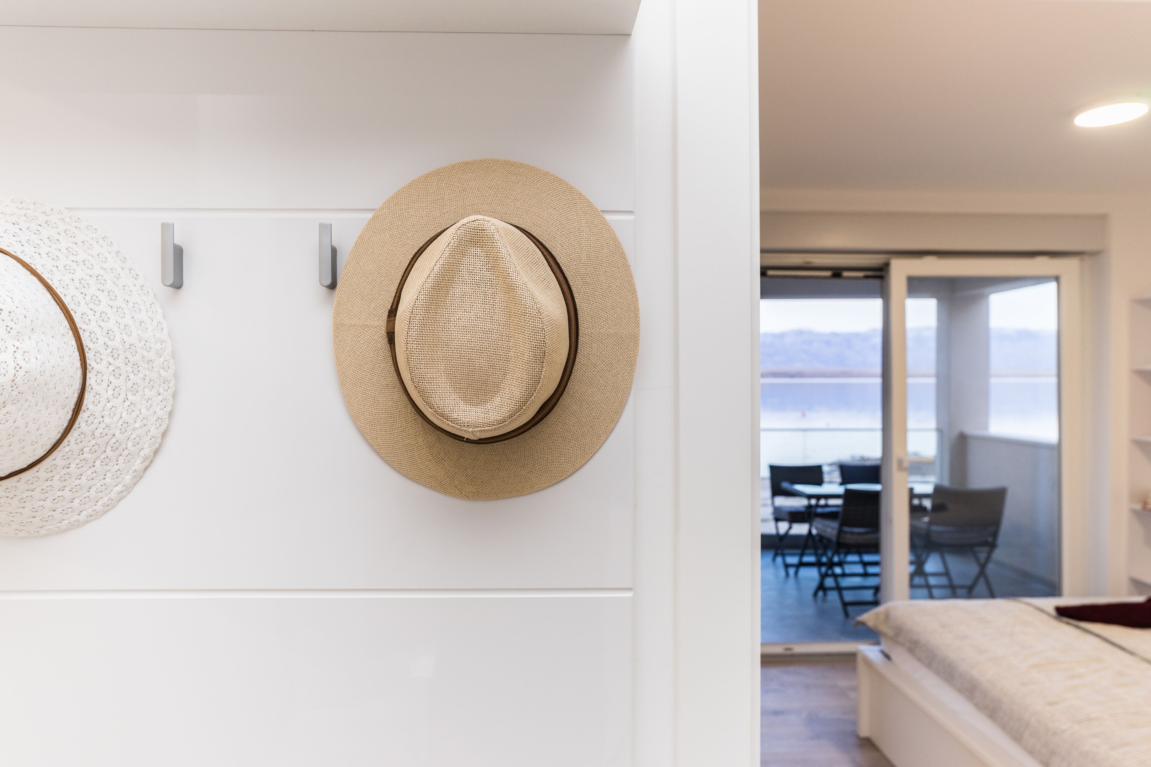 Una habitación con una cama, una zona de comedor con sillas y dos sombreros colgados en la pared.
