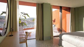 A hotel room with a bed, a desk, a chair, and a large window with curtains.