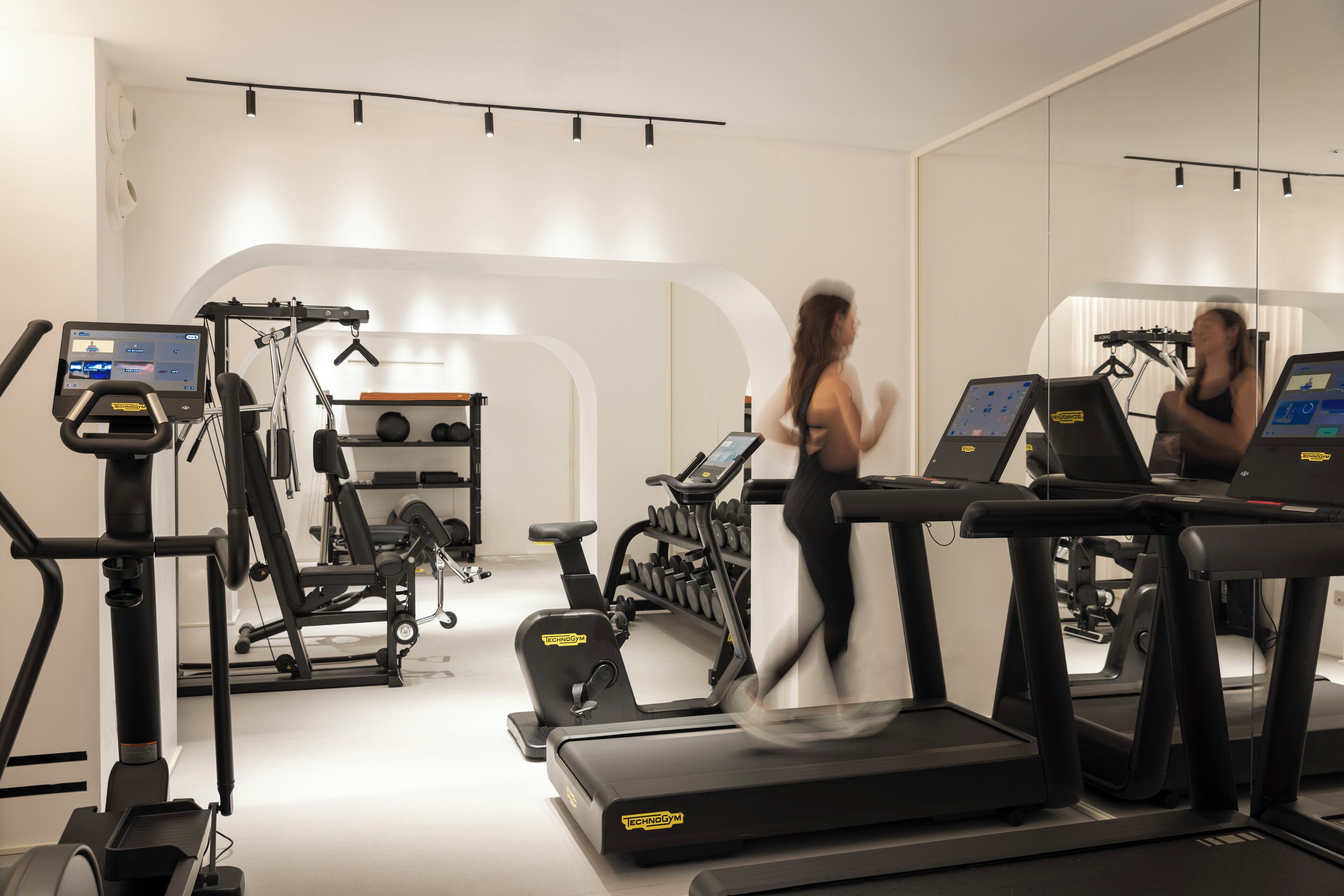 Un gimnasio con cintas de correr, bicicletas estáticas y máquinas de pesas.