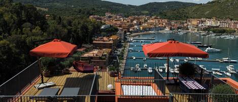 A rooftop terrace with outdoor seating and a view of a marina.
