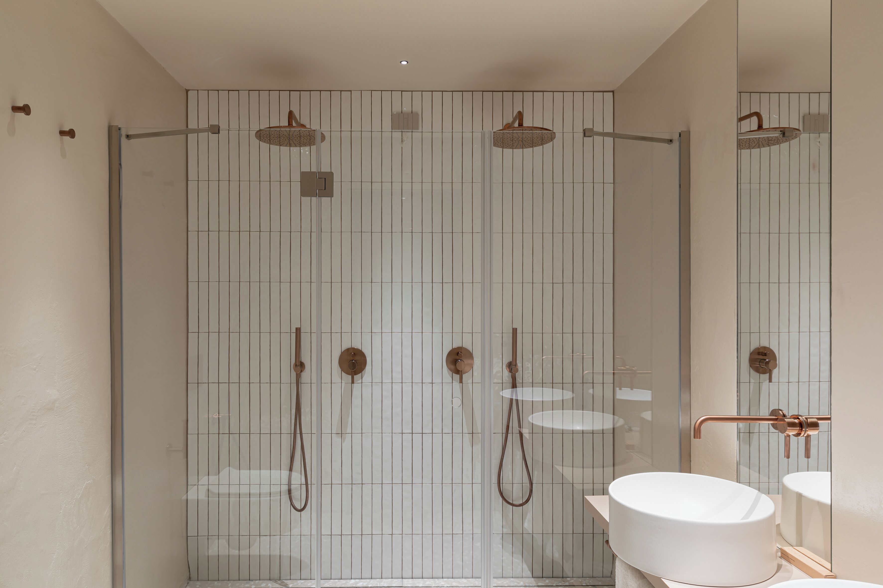A modern bathroom with a glass-enclosed shower, a round sink, and a mirror.