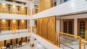 A multi-level interior with ornate golden doors and white walls. - Hotel The Dewan (Srinagar)