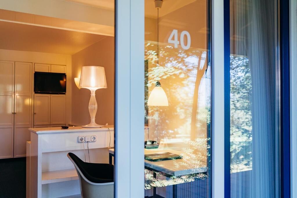 Ett hotellrum med ett skrivbord, en stol, en tv, en lampa och ett fönster med siffran ’40’ på.