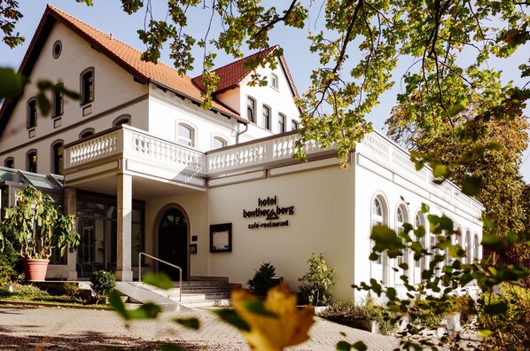 Ein historisches Gebäude mit weißer Fassade, Rundbogenfenstern und einem roten Ziegeldach.