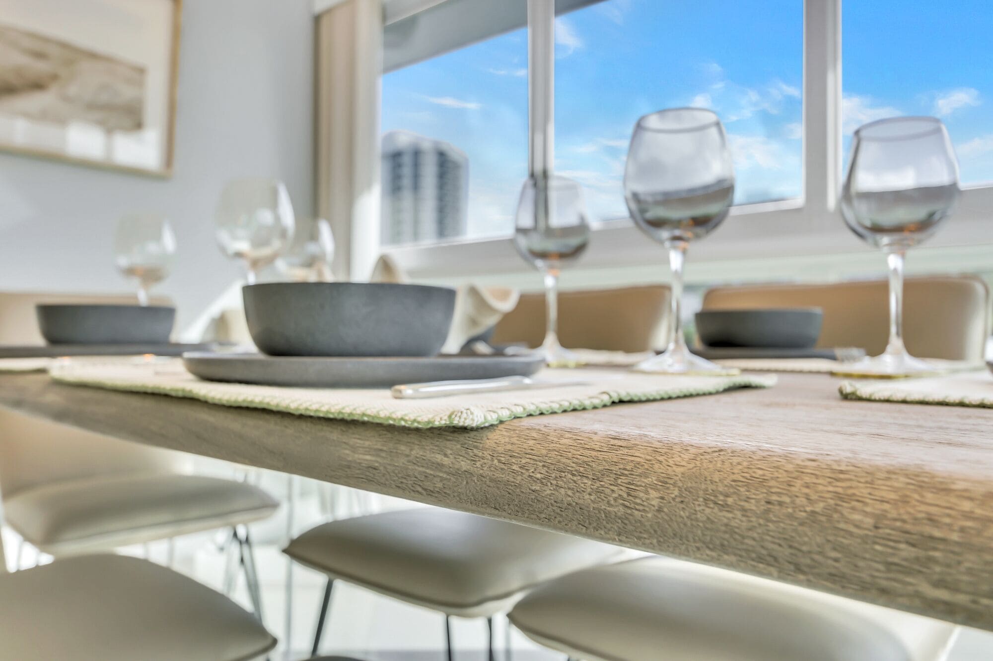 A dining table with multiple wine glasses and bowls, set with placemats.