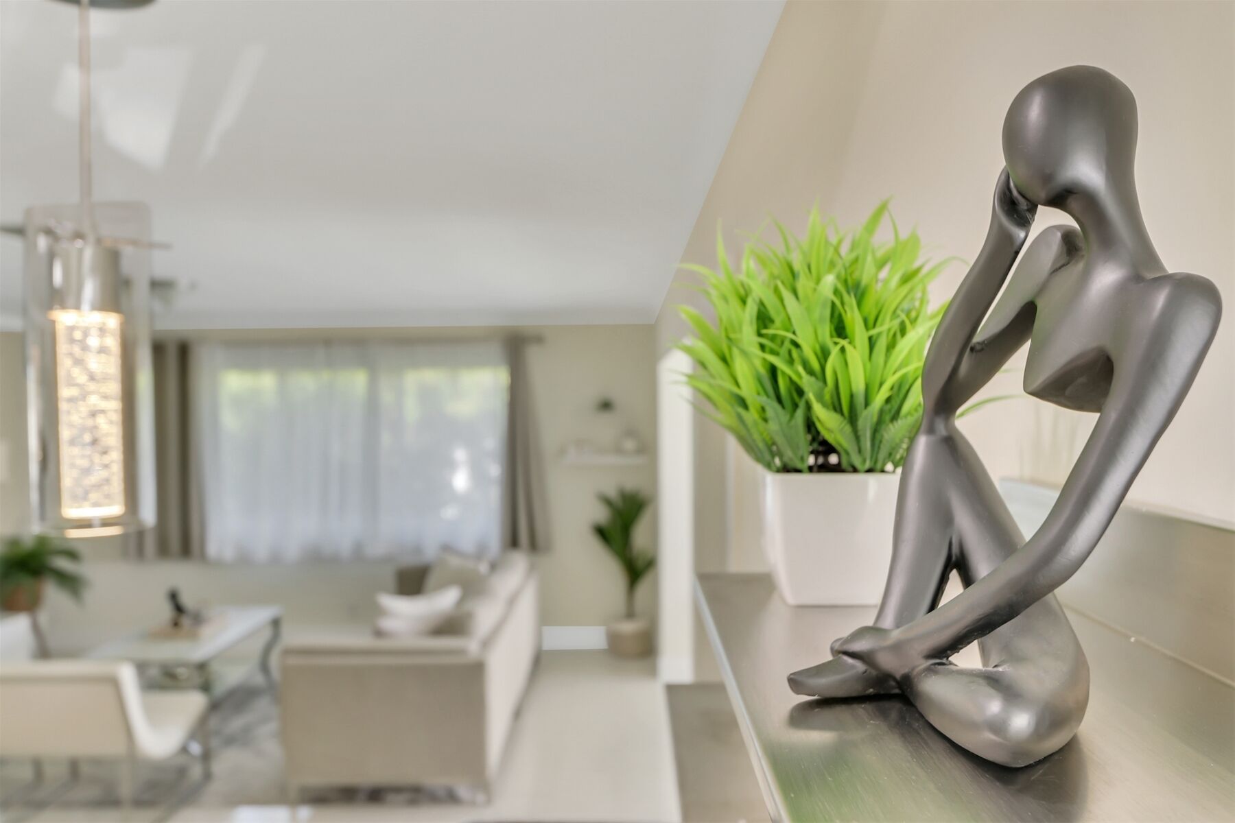 Un intérieur moderne au design minimaliste, comprenant un espace salon agrémenté d’une plante en pot et d’une sculpture.