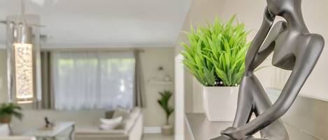 Un intérieur moderne au design minimaliste, comprenant un espace salon agrémenté d’une plante en pot et d’une sculpture.