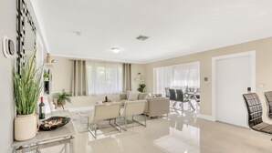 A spacious living room with a sofa, chairs, a dining table, and a kitchen area with a fridge and cabinets. - RiversideStar: Pompano Retreat, close to beach (Pompano Beach)