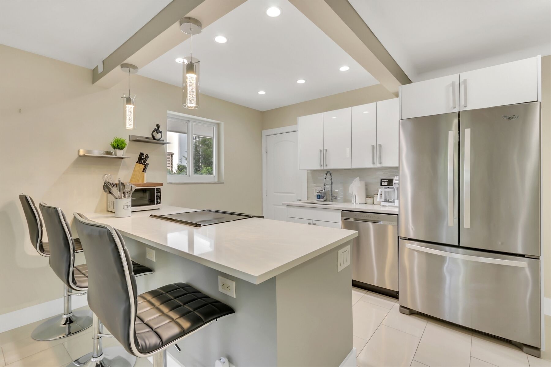 A modern kitchen with a central island, stainless steel appliances, and pendant lighting.
