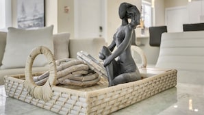A sculpture of a seated figure holding a child, placed on a woven tray with a basket and a rope. - RiversideStar: Pompano Retreat, close to beach (Pompano Beach)